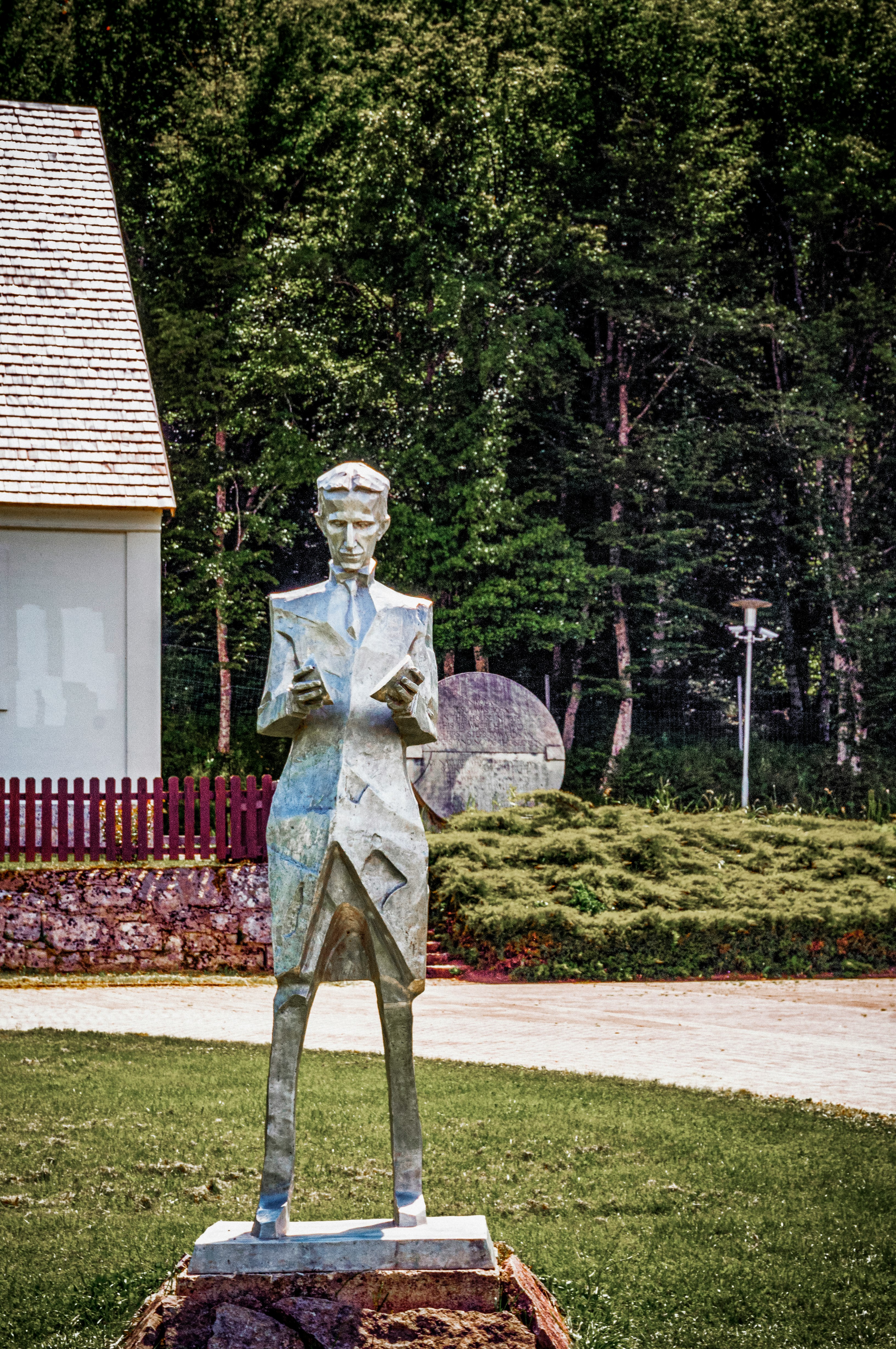 statue of man holding book near green grass field during daytime